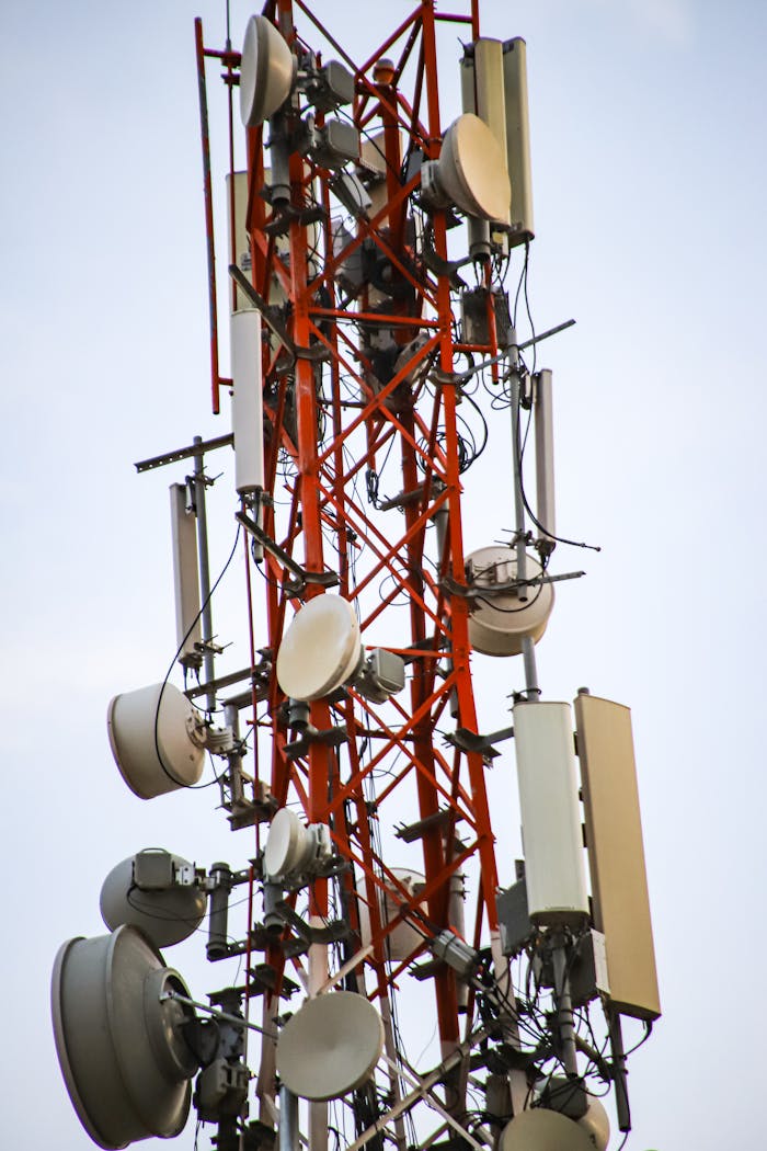 Home A close-up of a tall telecommunication tower with antennas and equipment against the sky.